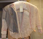 a%20cream%20lace%20blouse%20with%20a%20drape%20of%20grey%20gauze%20over%20the%20left%20shoulder